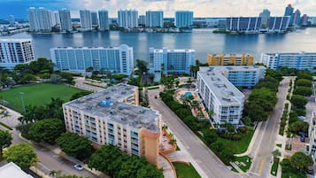 A high-rise hotel with multiple floors, a parking area, and a view of the water and other buildings.