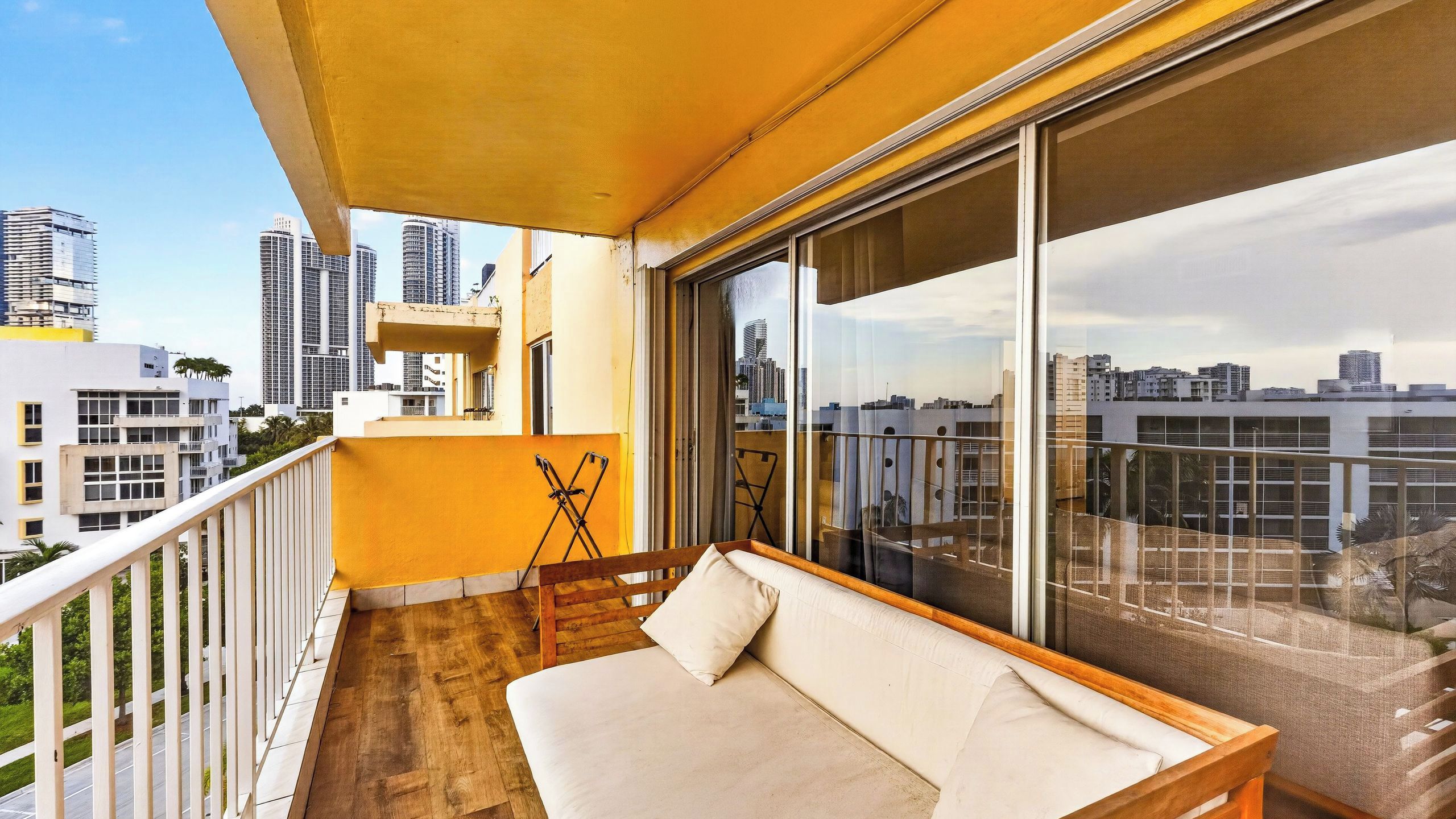 A balcony with a sofa, a small table, and a chair.