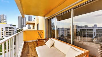 A balcony with a sofa, a small table, and a chair.