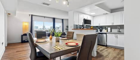 Un appartamento moderno con zona pranzo, cucina e ampie finestre con vista sulla città.