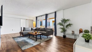 Ein modernes Wohnzimmer mit Sofa, Couchtisch und großem Fenster.