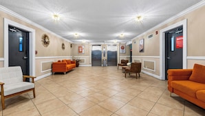 A lobby with a reception desk, two elevators, and seating areas with orange sofas. - Isle Vista by Avantstay Sunny Isles Condo Shared Pool + Private Balcony Near Beaches (Sunny Isles Beach)