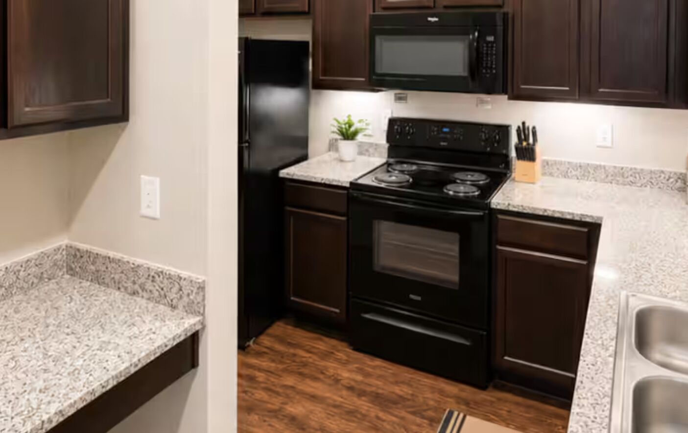 A kitchen with dark wooden cabinets, a black stove, and granite countertops.