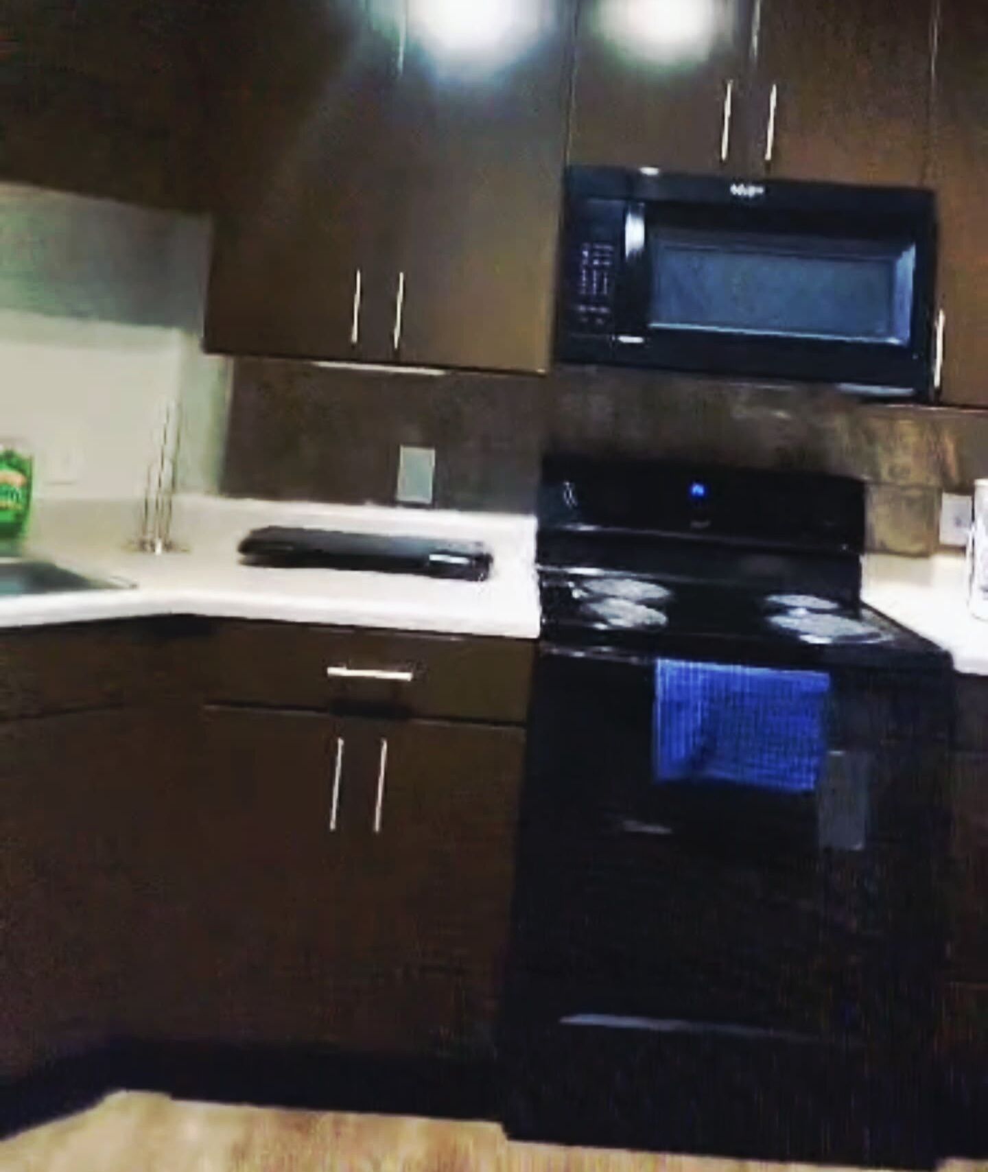 A kitchen with dark brown cabinets, a black microwave, and a black oven.