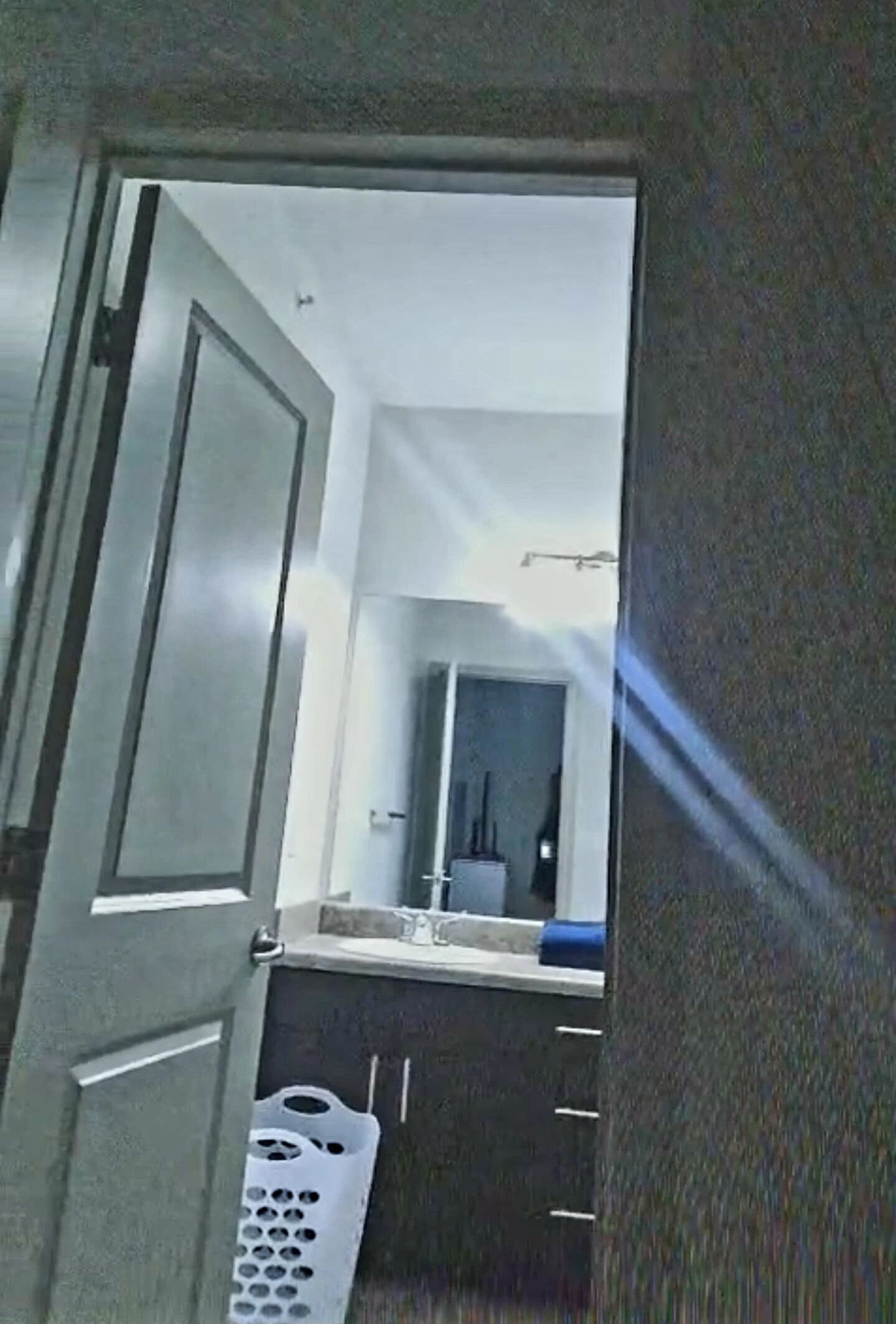 Une salle de bain avec un miroir, un lavabo et un panier à linge.