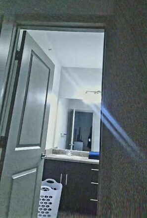 A bathroom with a mirror, a sink, and a laundry basket.