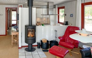 Un salon chaleureux avec un poêle à bois, un fauteuil en cuir rouge et une table à manger.