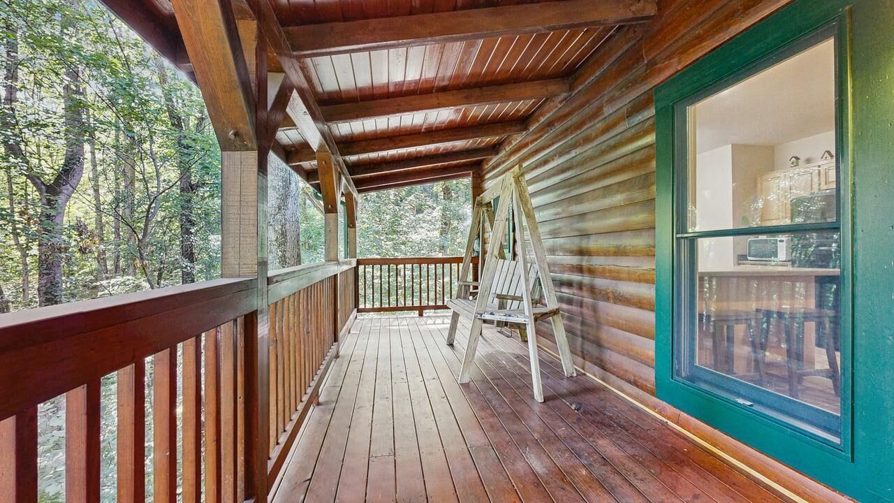 Een houten terras met uitzicht op het bos, een ladder en een raam met uitzicht op het interieur.