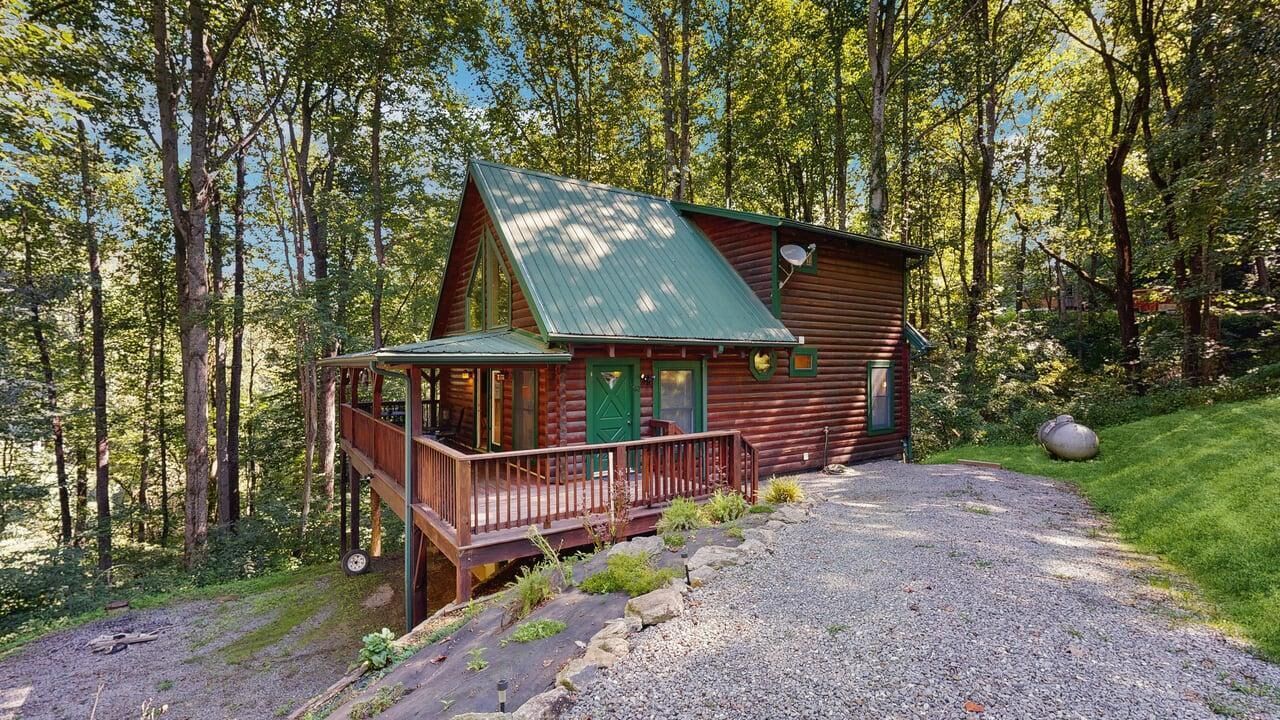 Een chalet met een veranda, omringd door bomen.