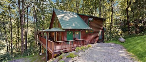 A cabin with a porch, surrounded by trees.