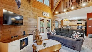 Ein gemütliches Wohnzimmer mit Kamin, einer Couch, einem Fernseher und einem Essbereich mit Tisch.
