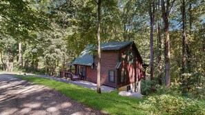 Eine Hütte mit Veranda, umgeben von einem Wald.