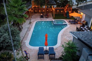 Un jardin avec une piscine, des chaises longues et un espace repas.