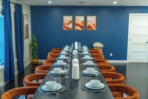 A long dining table set for a meal with orange chairs, blue walls, and a cactus plant. - Heated Pool, Spa, Golf, Bowling, Arcades, Firepit (San Antonio)