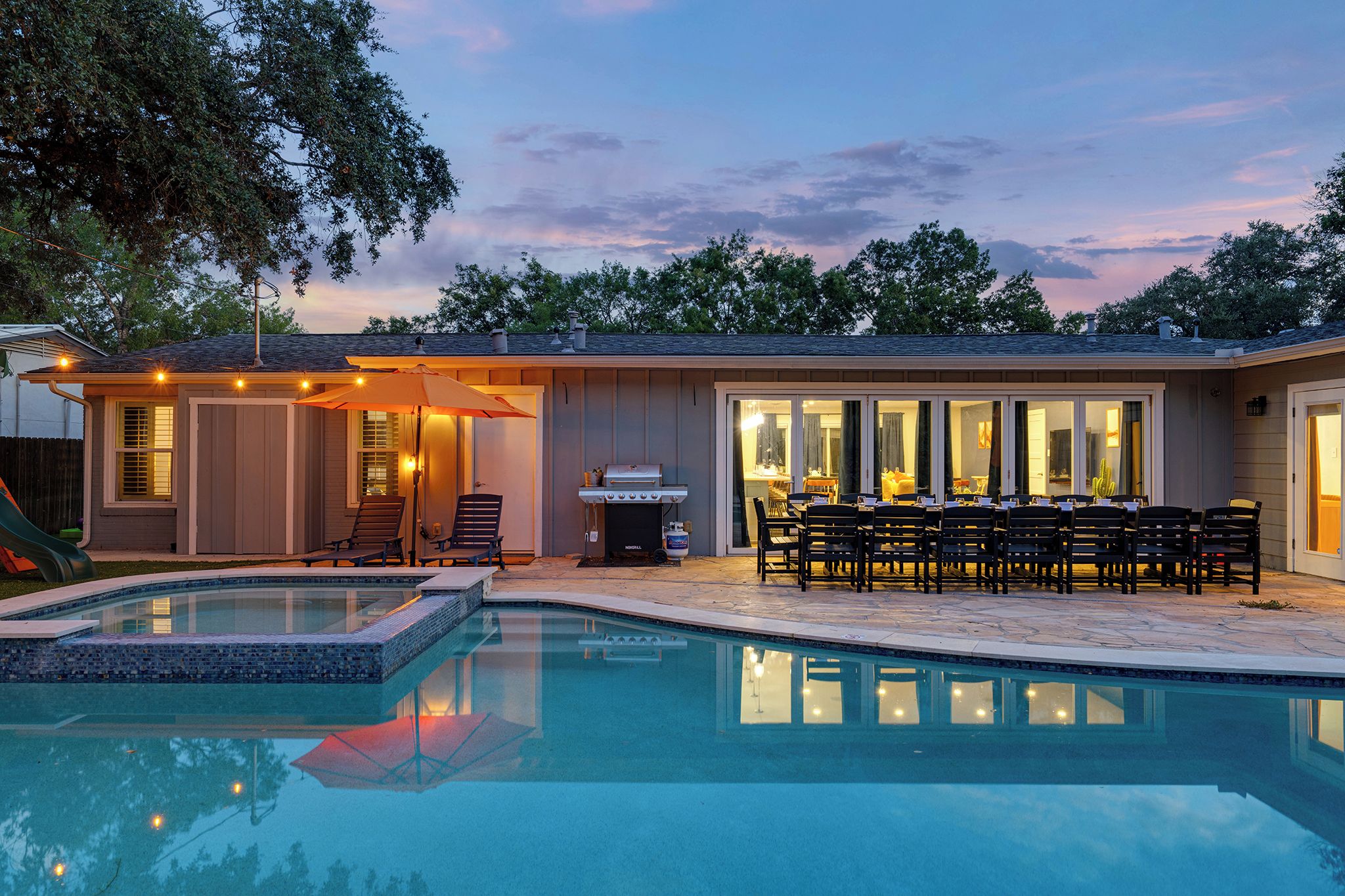 A swimming pool with a patio area, a barbecue grill, and outdoor seating.