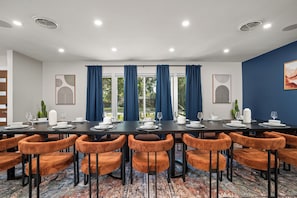 Une salle de conférence avec une longue table, des chaises recouvertes d’un tissu orange et un tapis à motifs.