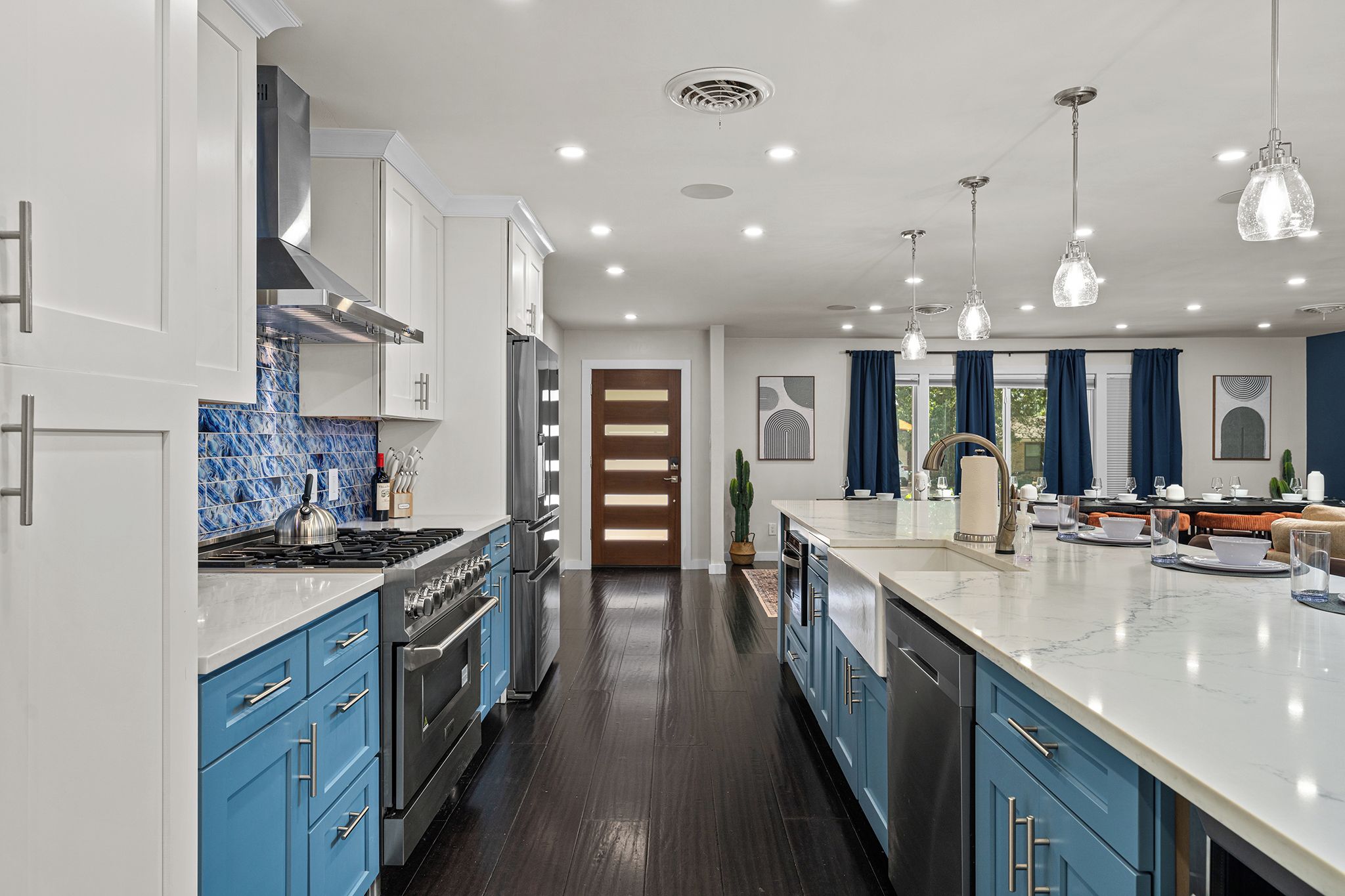 A modern kitchen with a central island, stainless steel appliances, and blue cabinetry.