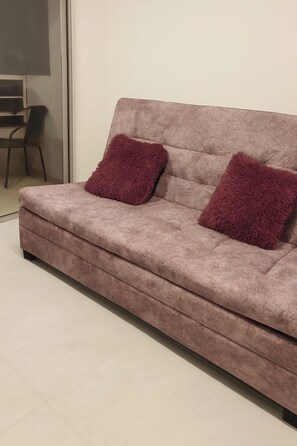 Ein Sofa mit zwei Kissen in einem Raum mit Fliesenboden.