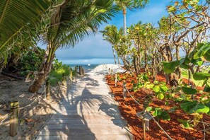A wooden pathway leading to a beach with palm trees and a clear view of the ocean. - Villa Capucine Beach Retreat | Pool | Games (Pompano Beach)