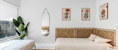 A bedroom with a bed, a bedside table, a mirror, and wall art.