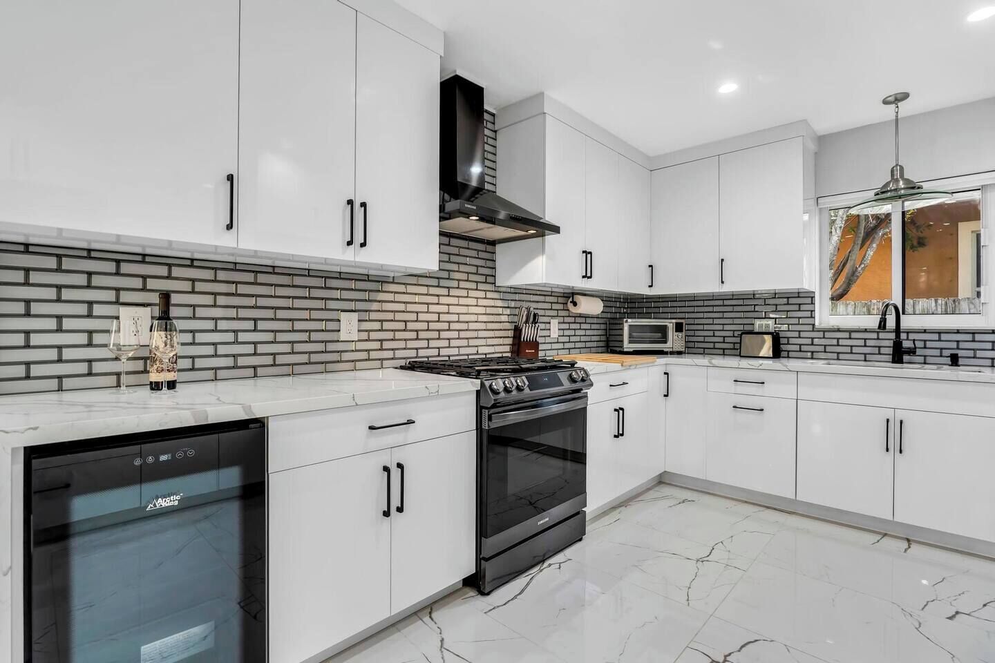 A modern kitchen with white cabinetry, a black stove, and a brick backsplash.