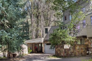 A two-story house with a stone facade, a covered garage, and a driveway leading to the entrance. - Booth Creek Lodge | 4BR East Vail Retreat, Sleeps 8 (Vail)