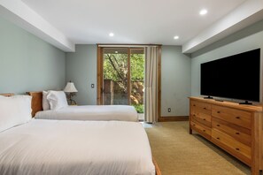 A hotel room with two beds, a TV, a dresser, and a sliding glass door to a balcony. - Booth Creek Lodge | 4BR East Vail Retreat, Sleeps 8 (Vail)