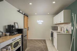 A compact kitchen with a coffee machine, microwave, and a neon sign on the wall. - Hot Tub, Sauna, Fire Pit, Huge Yard near Denver and Red Rocks (Arvada)
