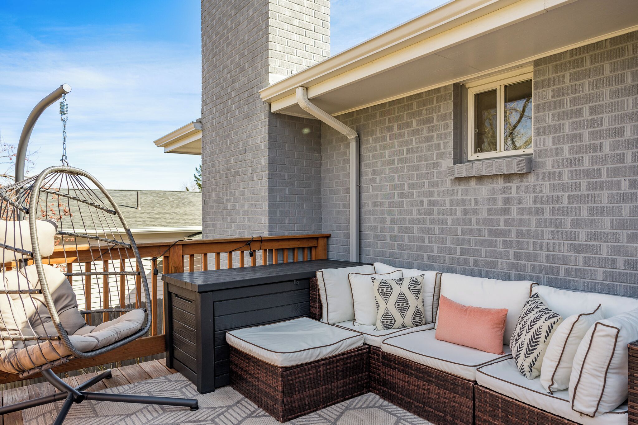 A patio with a wicker sofa, a hanging chair, and a small table.