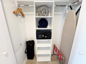 A white closet with shelves, a black safe, and a black bag. - Stylish Resort Studio at Beachwalk w/ Bay View (Hallandale Beach)