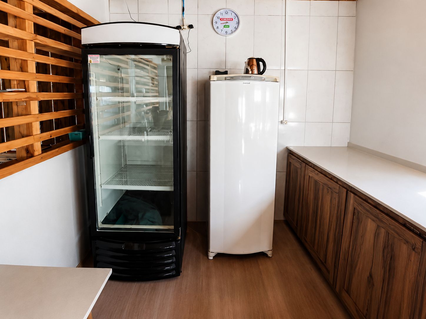 Una cocina con un refrigerador, un reloj y armarios de madera.