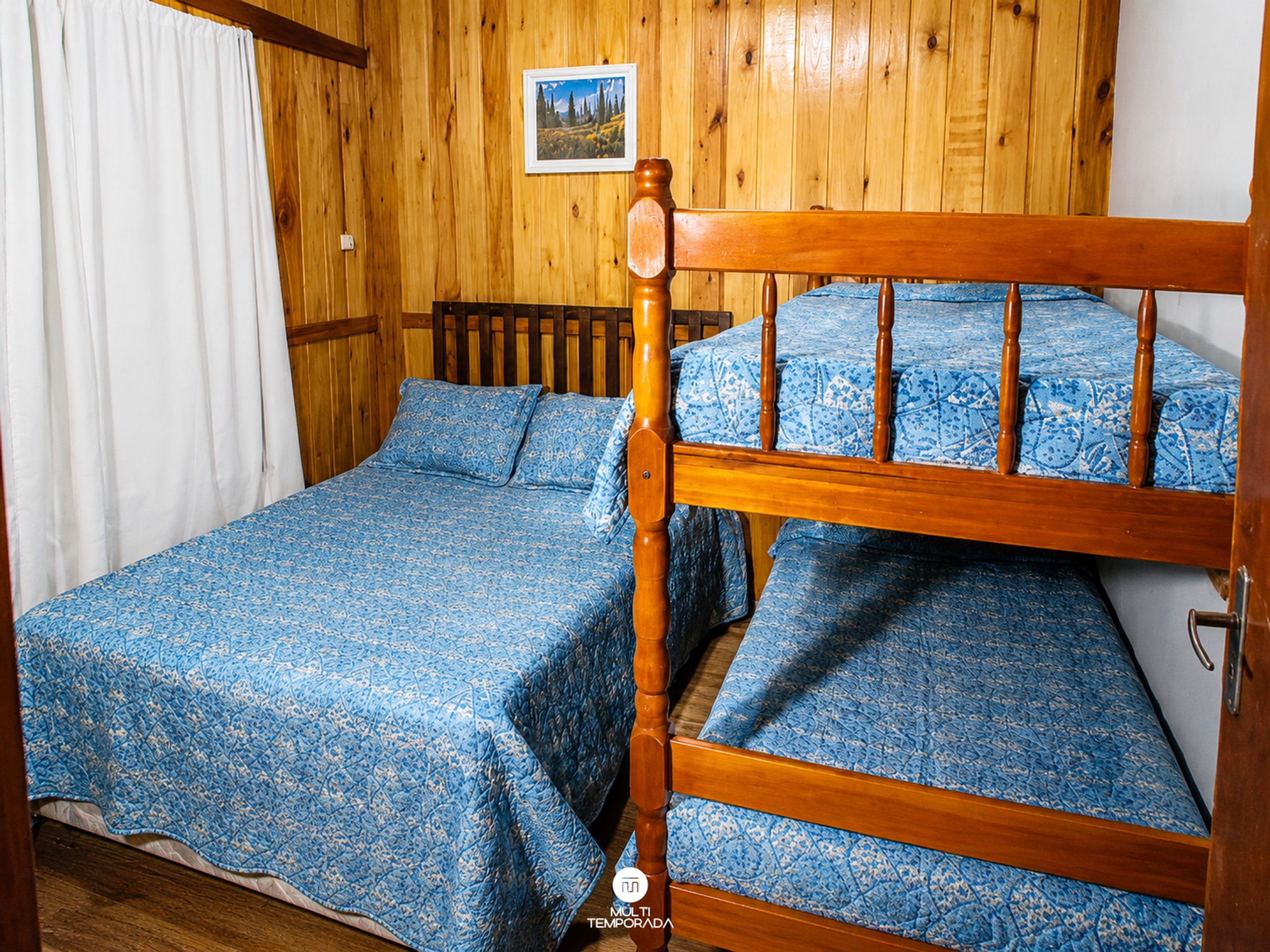 A wooden bunk bed with a blue patterned bedspread and matching pillows.