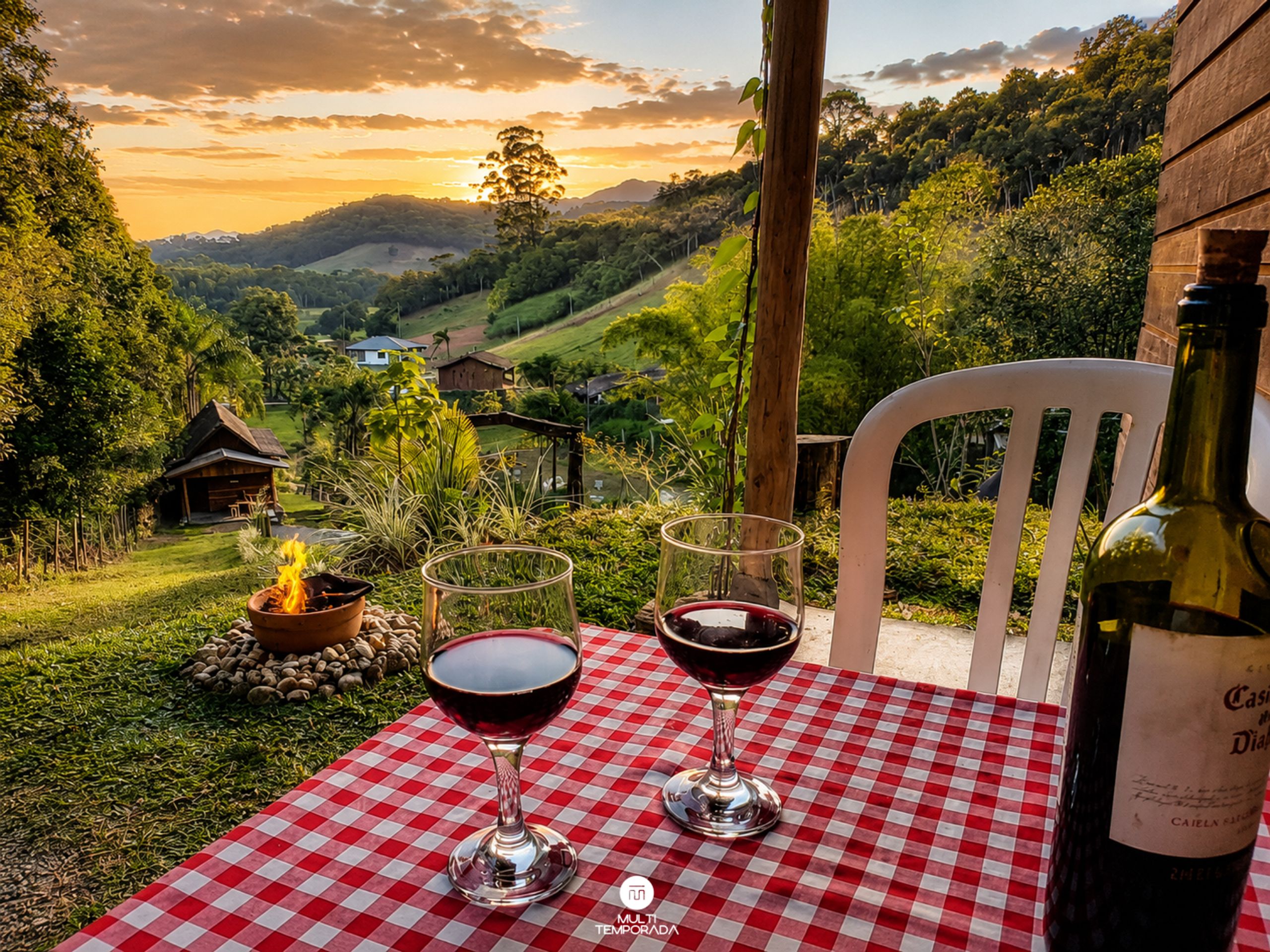 A table with a checkered tablecloth, two wine glasses, and a bottle of wine, set against a scenic backdrop of a valley and a sunset.