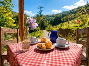 A picnic setup with a checkered tablecloth, a bottle, cups, and biscuits on a table. - Colina Verde EcoPark - Canelinha - SC (Canelinha)