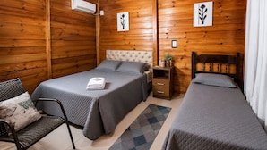 Une chambre avec deux lits, un banc et une petite table sur laquelle est posée une plante.