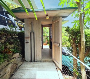 A wooden staircase leading to a covered outdoor area with a view of the sea.