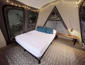 A bedroom with a bed, pillows, a bedside table, and a lamp.