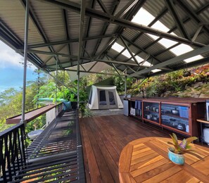 A covered outdoor area with a wooden deck, a tent, and a display cabinet with items.