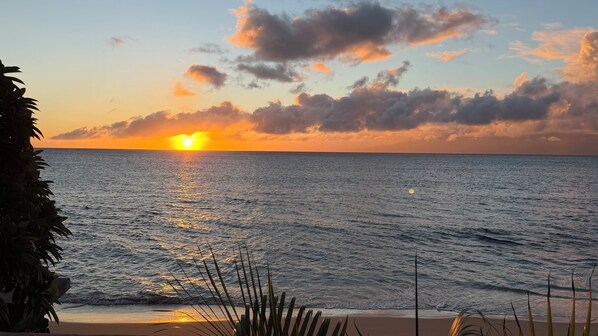 Ein Sonnenuntergang über dem Meer mit Wellen und wolkenlosem Himmel.