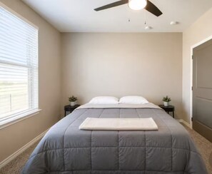 A bedroom with a bed, ceiling fan, two bedside tables, and a window with blinds. - The Midlothian Hideaway - Modern 1BR Extended Stay (Midlothian)