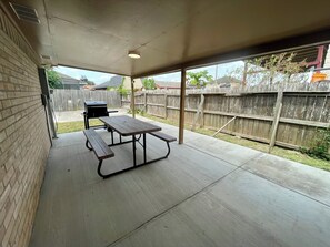 Un patio techado con mesa de picnic y parrilla.