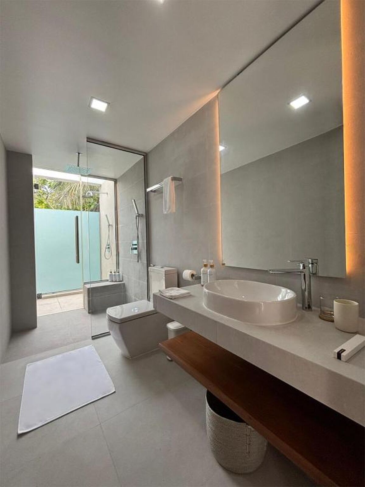 Une salle de bain moderne avec un grand miroir, un lavabo rond et un espace douche.