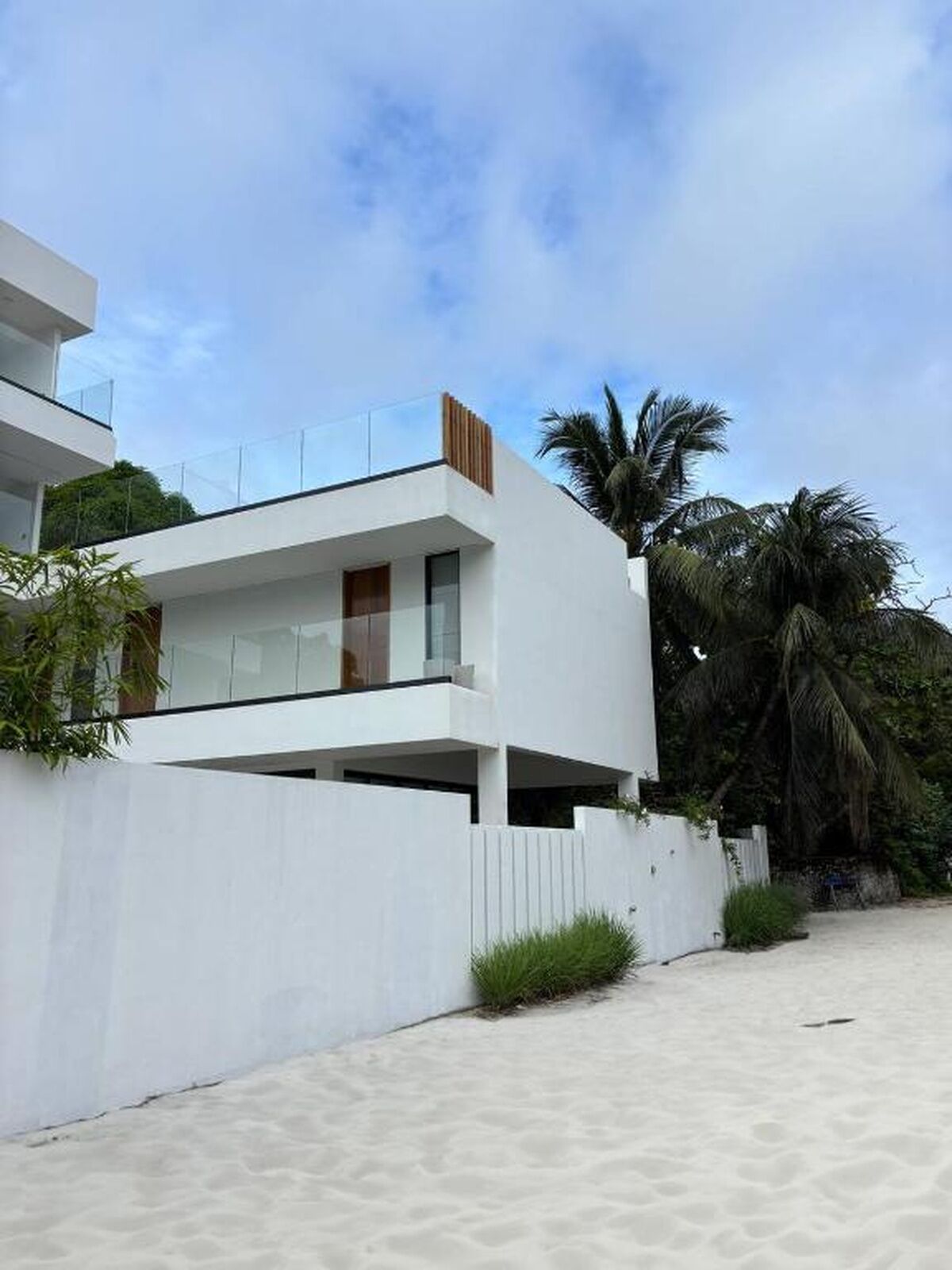 A modern two-story building with a flat roof, large windows, and a balcony.