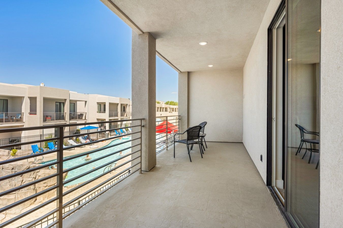 A balcony with a view of a swimming pool and adjacent buildings.