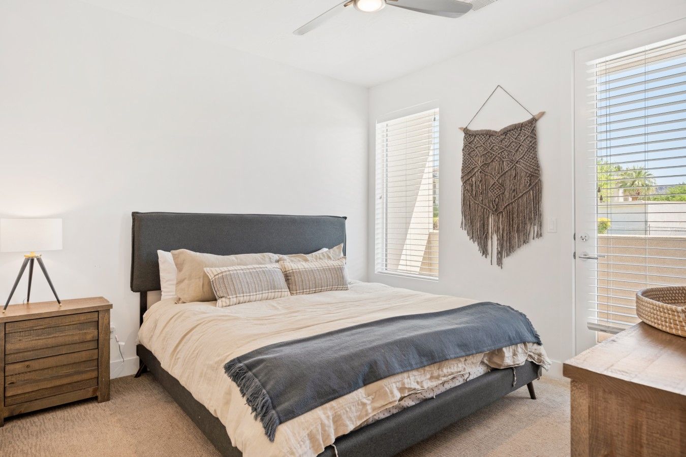 A bedroom with a bed, bedside table, lamp, and a view through a window.
