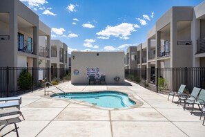 A pool area with a rectangular pool, surrounded by a low fence, and multiple lounge chairs. - Poolside Family Retreat, Sleeps 14 (St. George)