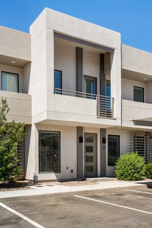 A modern two-story building with a flat facade, large windows, and a small balcony.