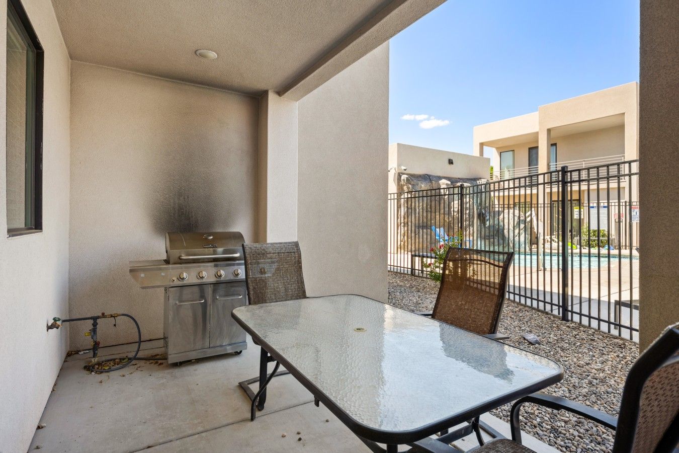 An outdoor patio with a grill, a table, and chairs.