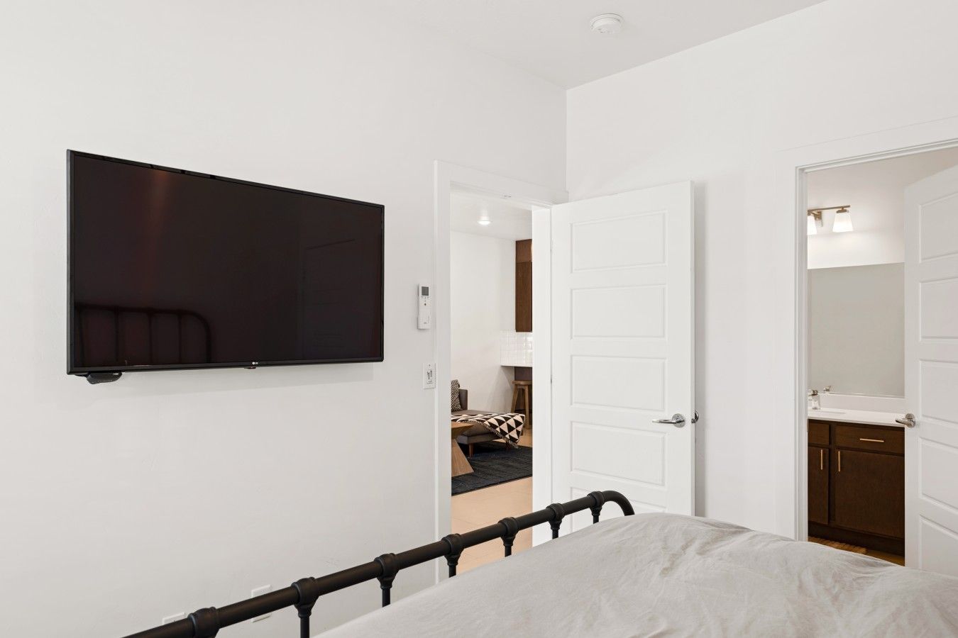 Une chambre à coucher avec un lit, un téléviseur fixé au mur et une porte donnant accès à une salle de bain.