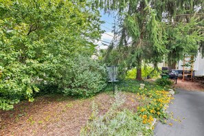 A garden with a variety of plants, a metal sculpture, and a paved path. - Peaceful Hideaway Perfect For Extended Stays (Indianapolis)